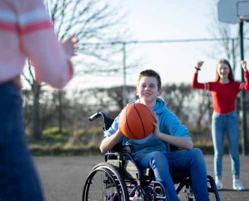 Bursche im Rollstuhl spielt Basketball Freunden