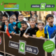 Eine Gruppe jubelnder und anfeuernder Kinder und der Text: Servus bewegt Kinder - Die bewegte Schule. motion4kids. Anmeldung ab Herbst.