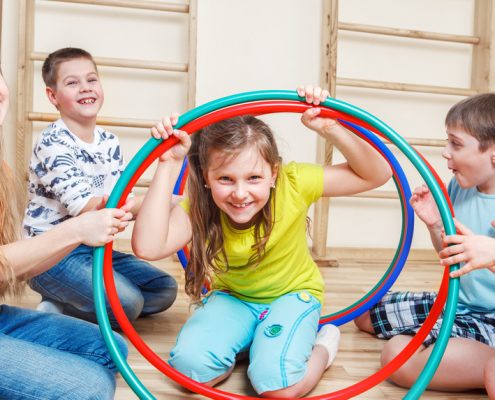 Fröhliche Kinder spielen mit Hulahoop-Reifen