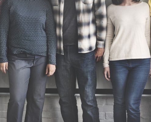 5 Personen stehen eng neben einander vor einer weißen Wand