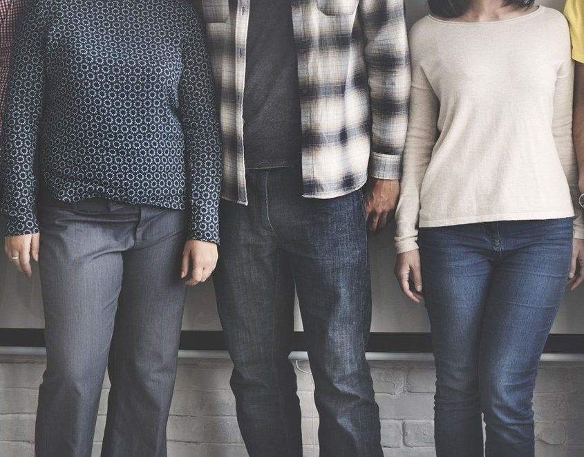 5 Personen stehen eng neben einander vor einer weißen Wand