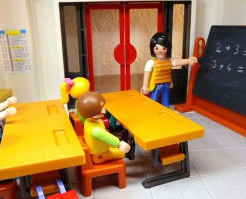 Ein Playmobil-Klassenzimmer mit Lehrerin an der Tafel und vier Schülerinnen und Schülern